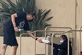 Myke Scholl serving a wholesome meal to a homeless community member in Long Beach, California