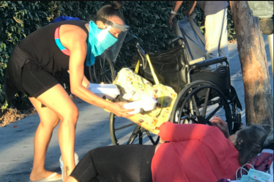 Sheenagh Scholl providing meal and mask to a homeless man in Long Beach, California